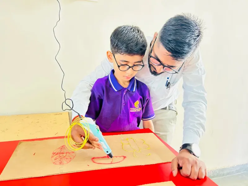 Student learning with a 3D printing pen in the robotics lab